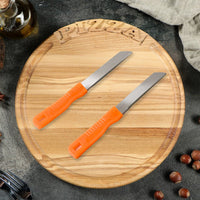 Stainless steel kitchen knife expertly slicing fresh vegetables on a cutting board.