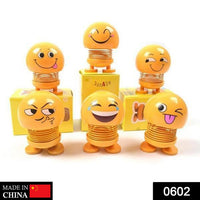 Front view of a funny bobblehead smiling face spring doll for desk decor.