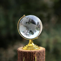 Elegant Crystal World Globe with golden stand, displayed next to a book and pen for desk decor.