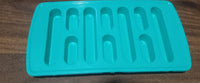The ice tray placed next to a glass of water with ice, highlighting its practical use.
