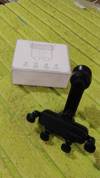 Car interior view showing the phone holder installed vertically on an air vent with a phone.