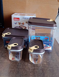 Set of four clear airtight food containers on a kitchen counter.