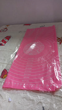 Hands rolling dough on the silicone baking mat, utilizing its non-stick property and guides.