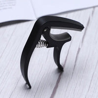 Guitar capo and pick holder positioned on a guitar neck, ready for playing.